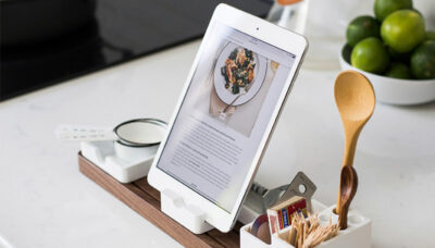 Tablet set up on a white countertop with a few kitchen spoons and fresh limes in view.