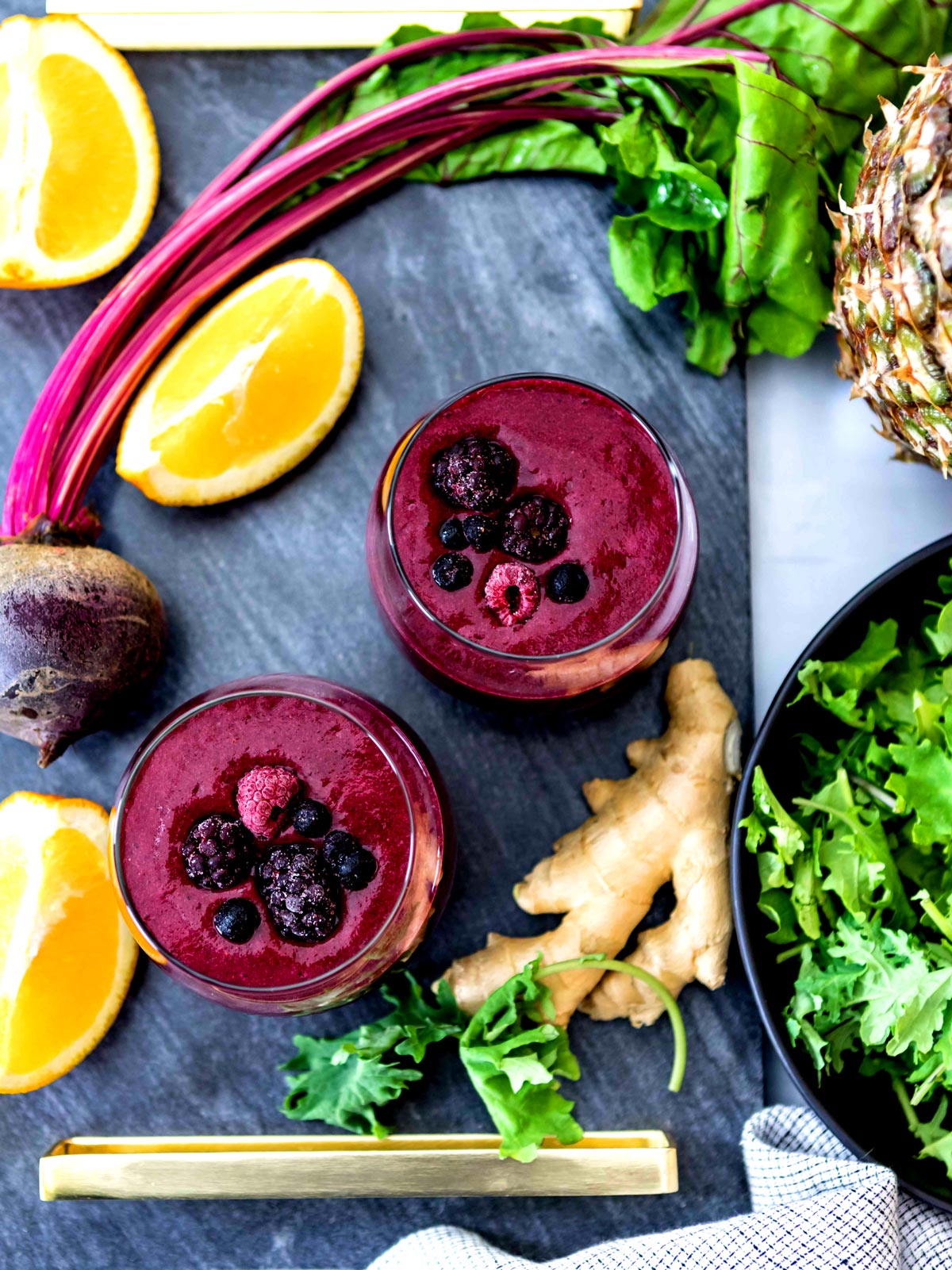 Foods to help with inflammation on a countertop like ginger root, kale lemon slices, and beets.