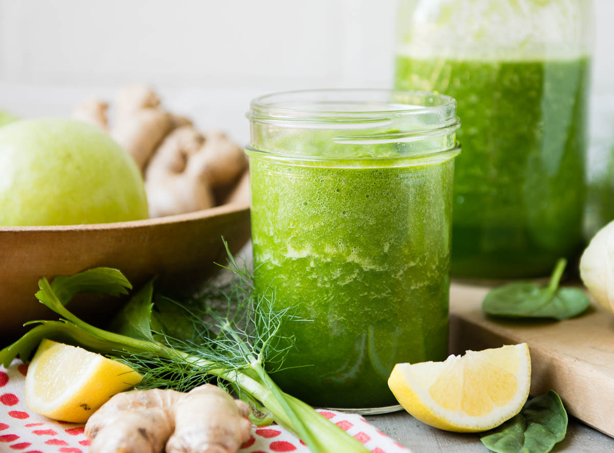 green smoothie in glass jar surrounded by fennel and sliced lemons.