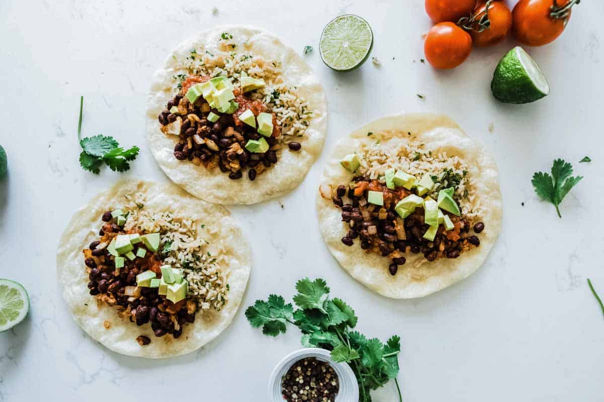 3 bean burritos with rice, avocado and salsa, not yet rolled up.