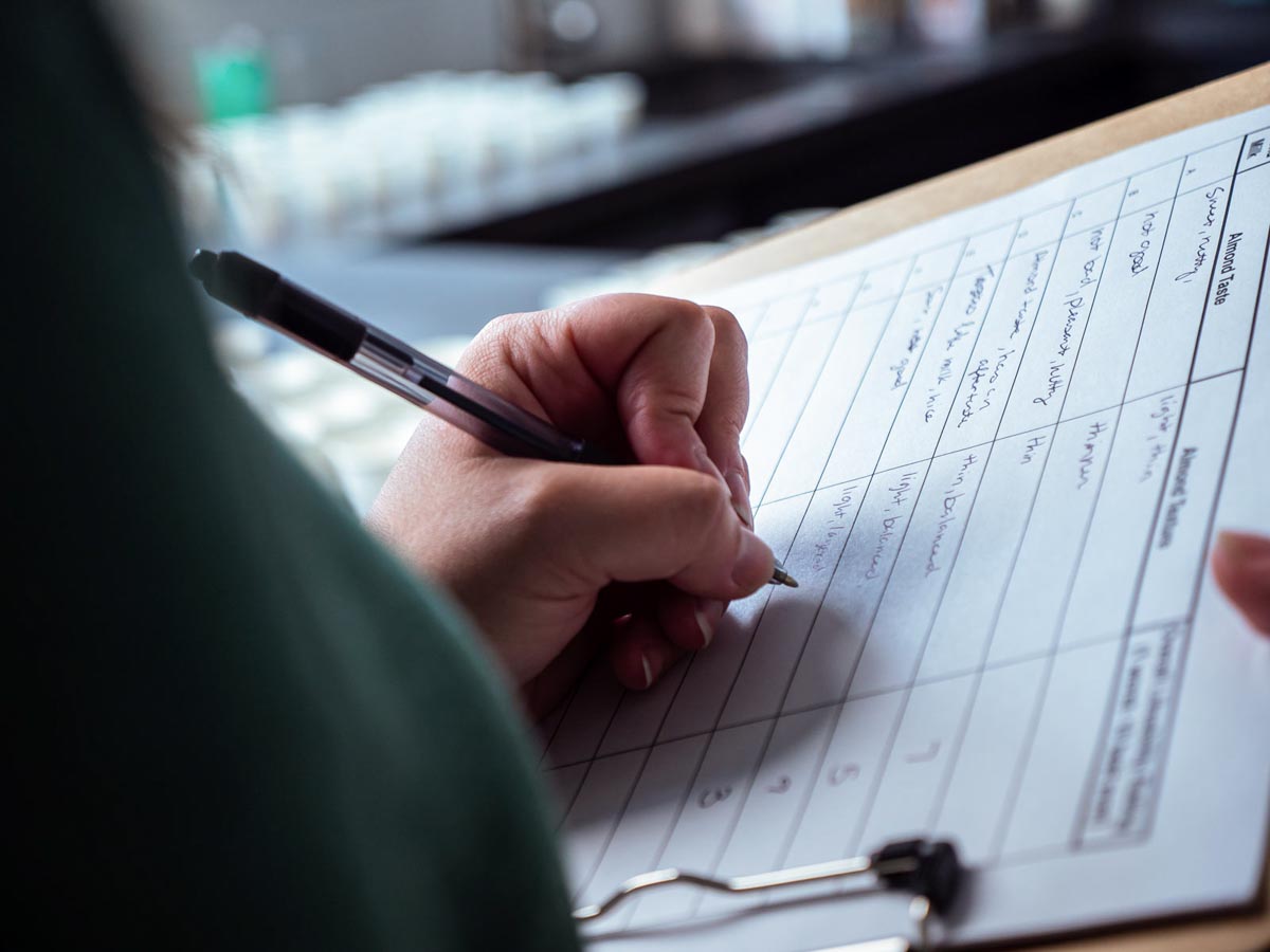 pen in hand writing notes on a clipboard.