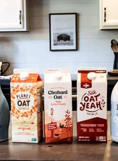 5 oat milk containers lined up on a kitchen counter, ready to be tested for the best oat milk brand.