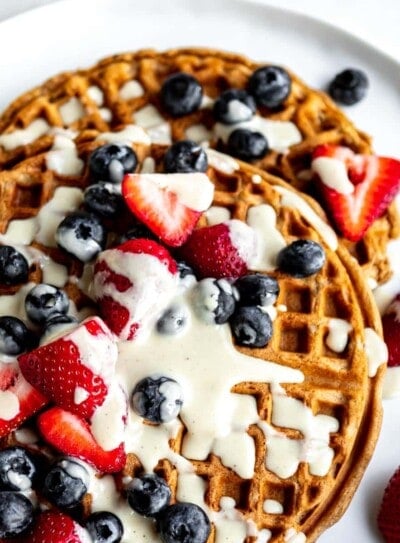 best vegan waffles topped with cream and fresh berries