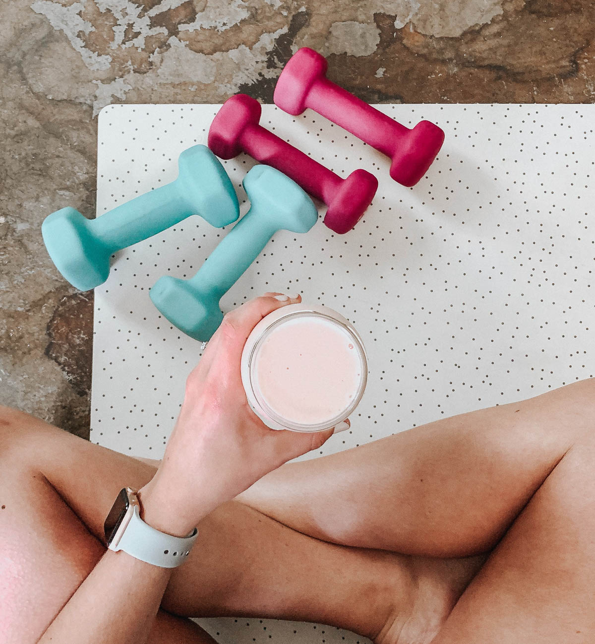 A person holding a drink next to some weights.