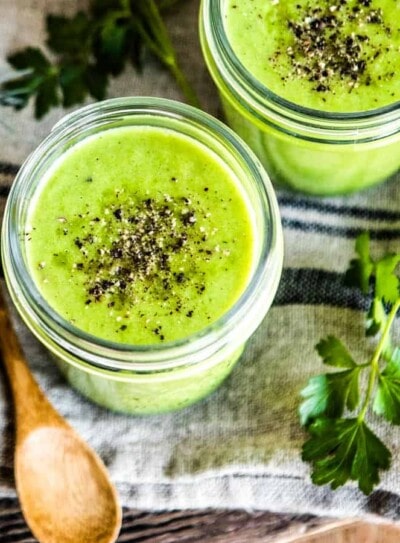 blended vegetable soup recipe in 2 glass mugs with wooden spoons.