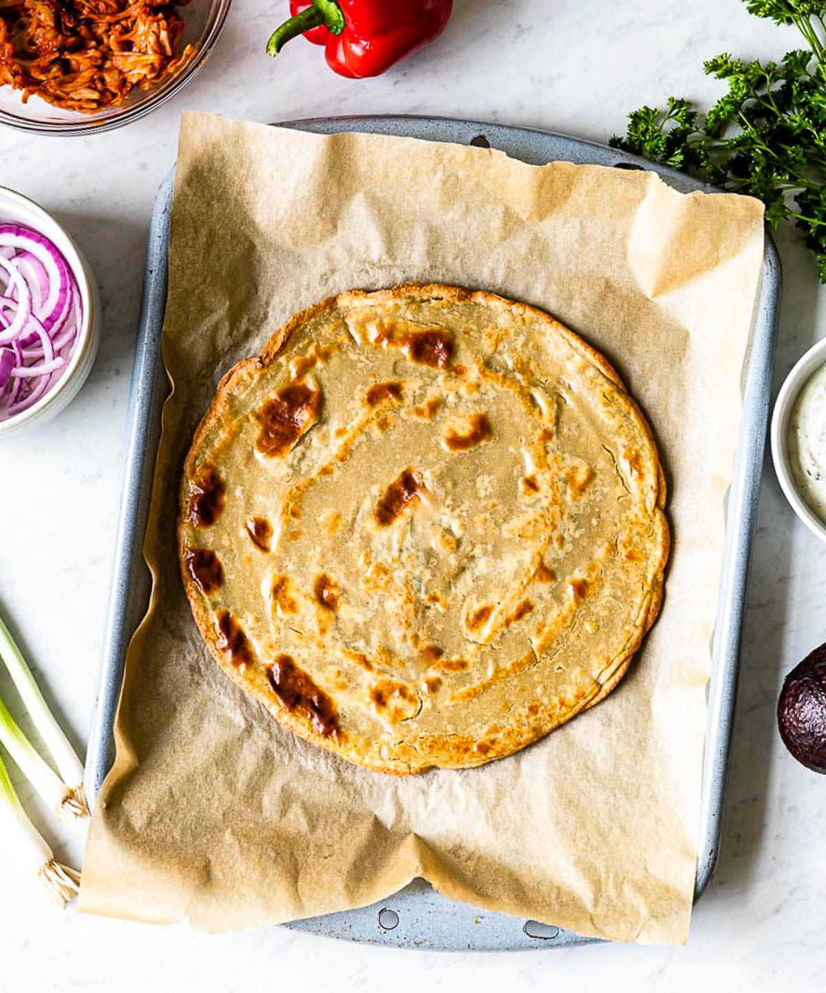 baked gluten-free pizza crust on a parchment lined baking tray.