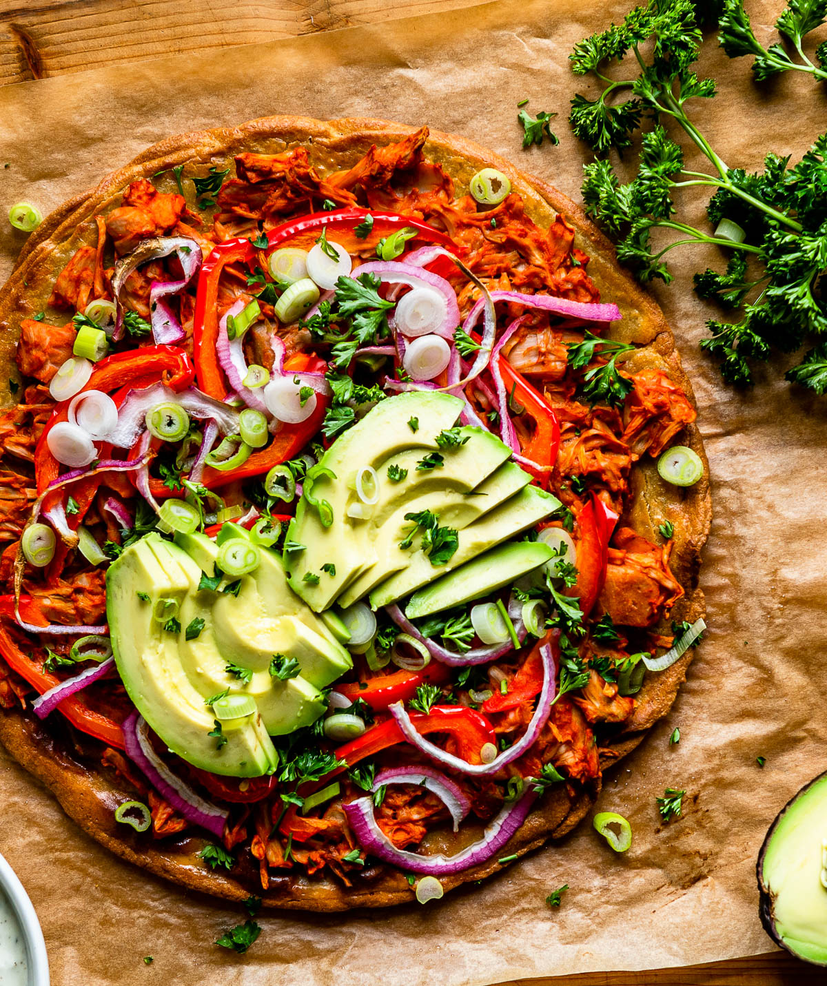 buffalo jackfruit pizza topped with sliced avocado.