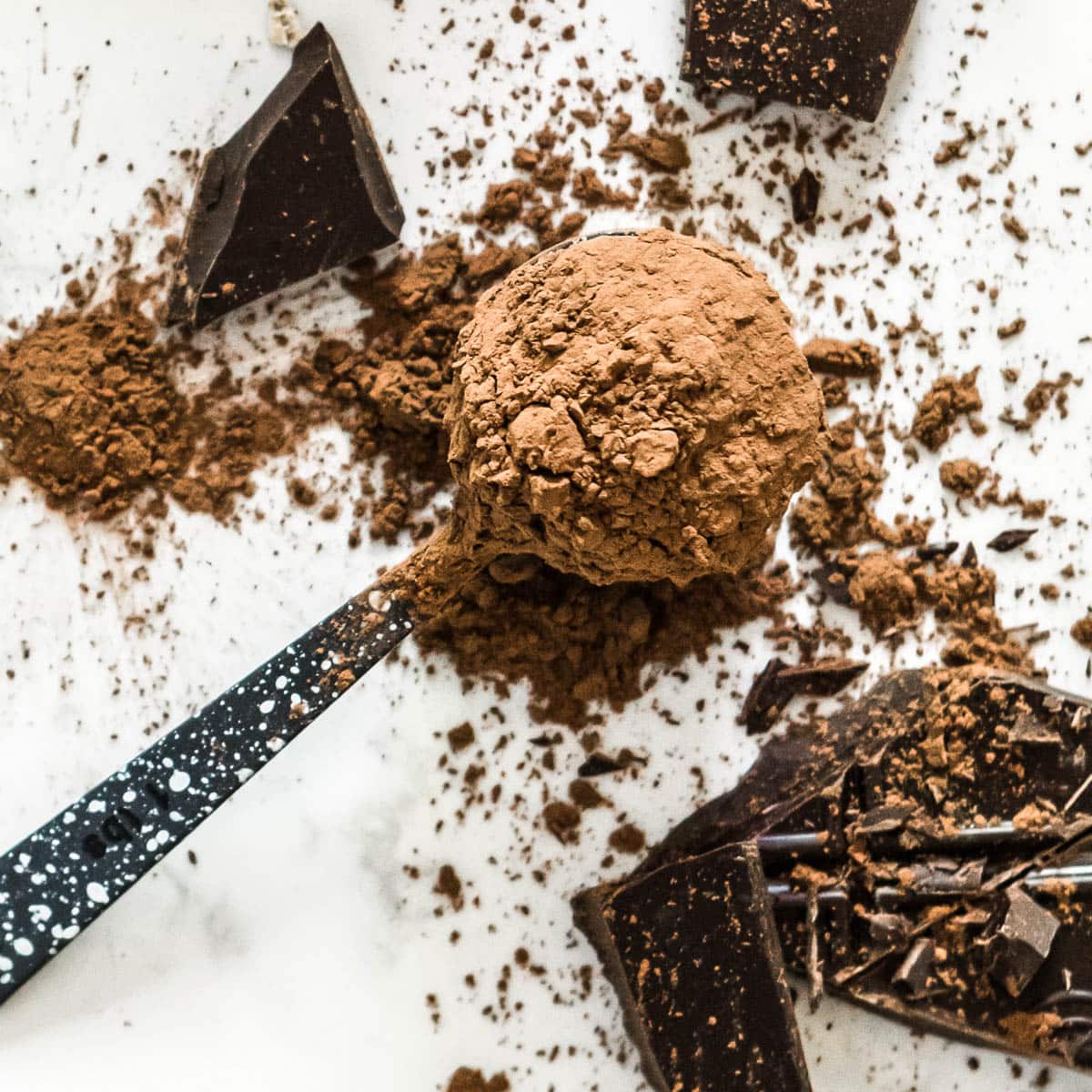 spoonful of cacao powder and broken pieces of chocolate in this cacao powder recipes round up.