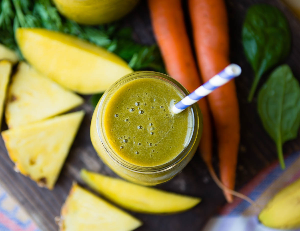 green smoothie in a glass jar with a striped paper straw.