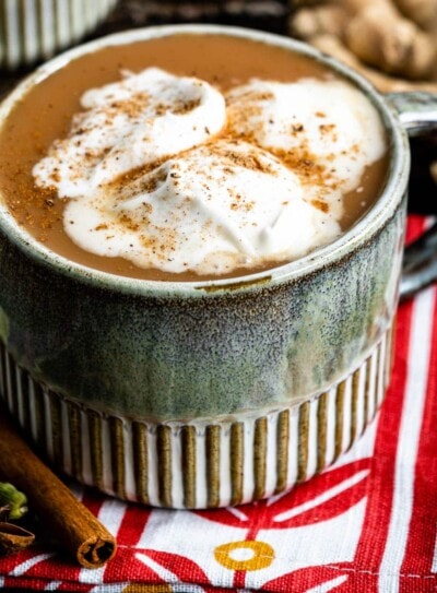 chai tea latte in a mug topped with homemade coconut whipped cream.