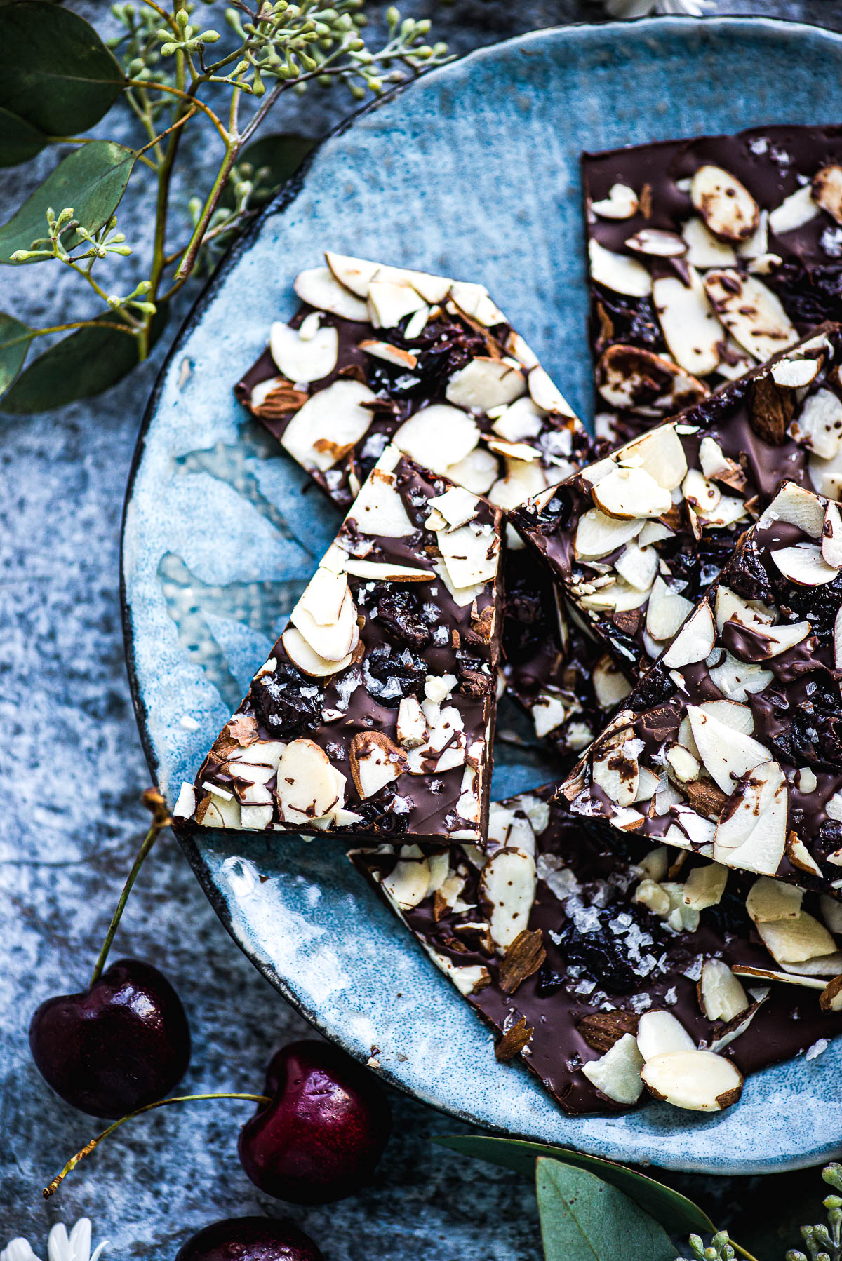 Fresh cherries next to a plate of cherry chocolate bark.