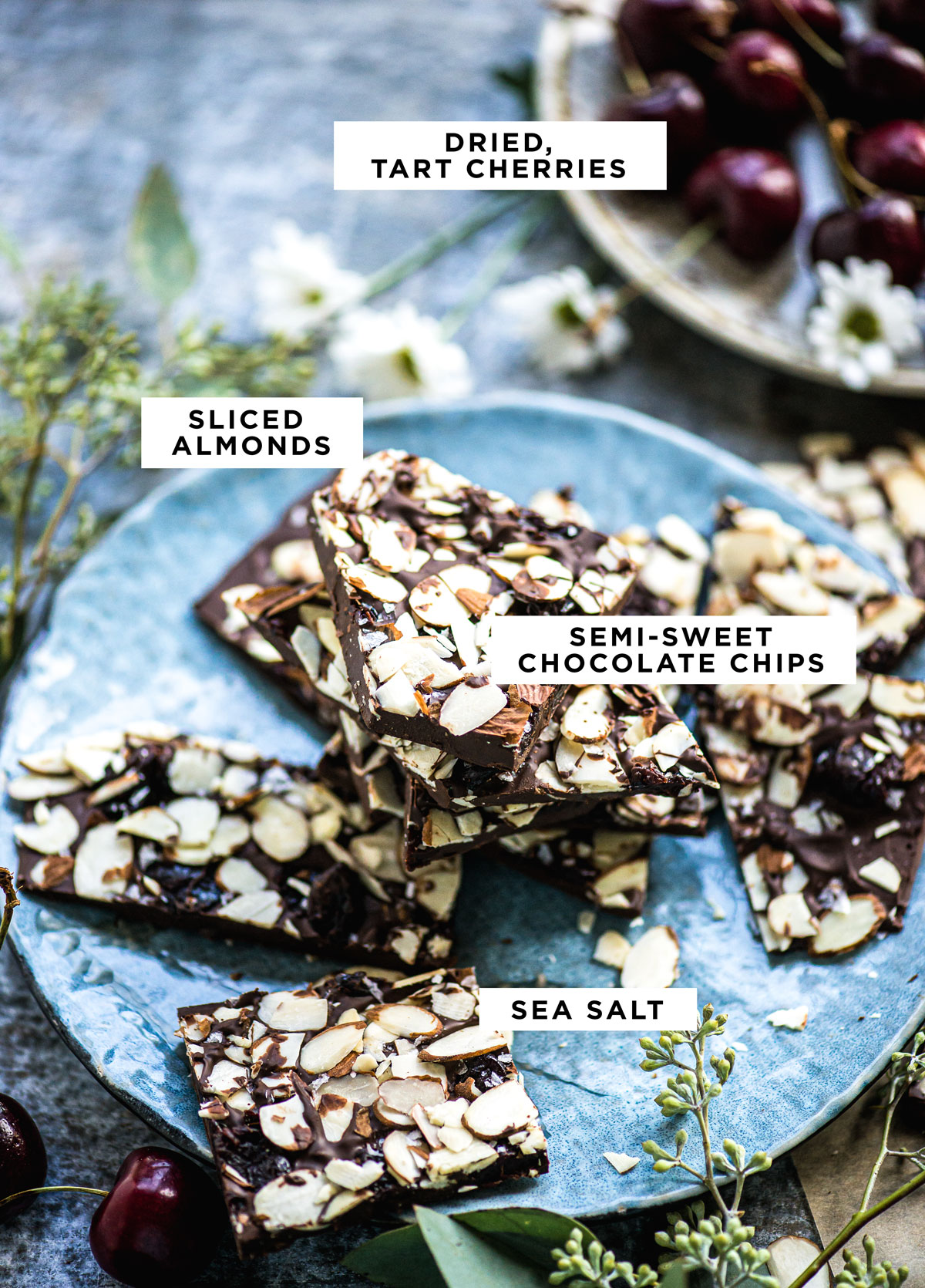 labeled ingredients for cherry chocolate bark including dried tart cherries, sliced almonds, semi-sweet chocolate chips and sea salt.