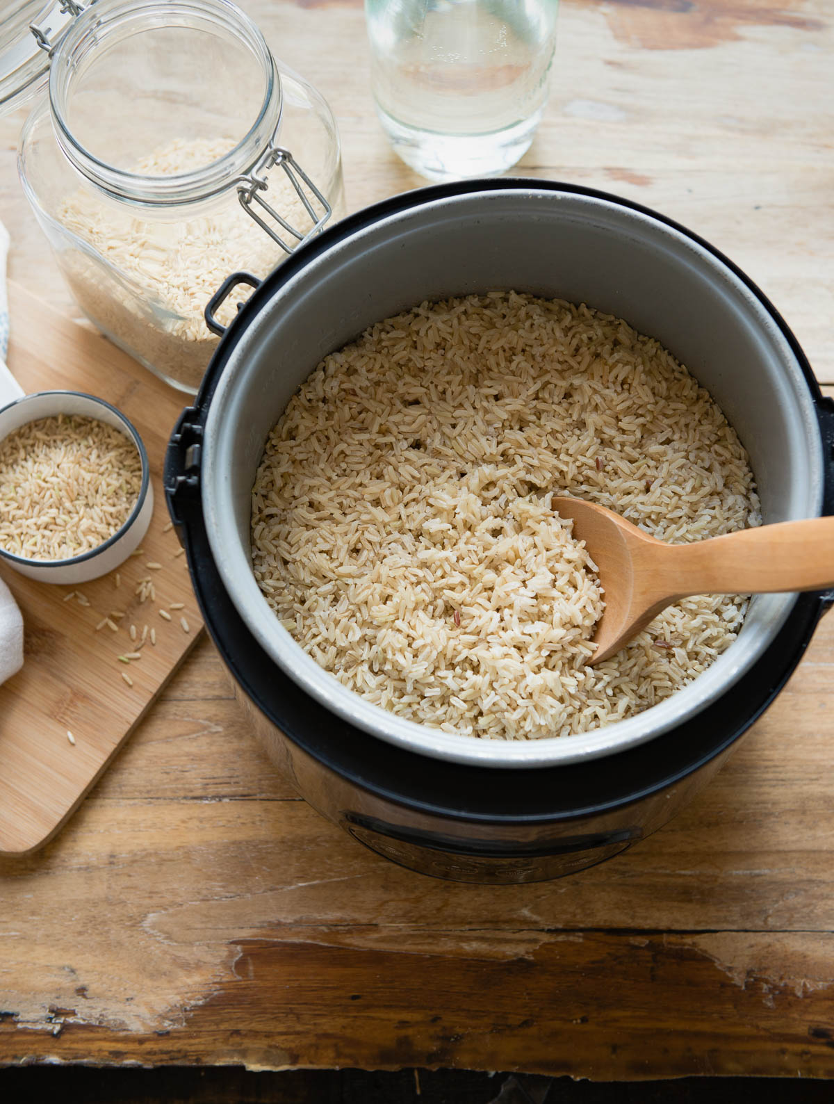 brown rice getting scooped out of a rice cooker with a wooden spoon.