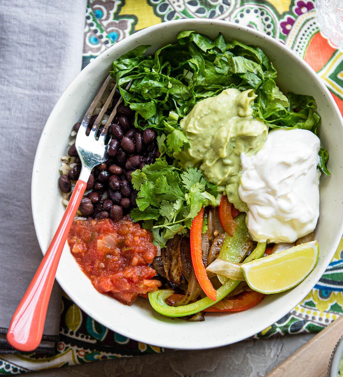 veggie burrito bowl in a white bowl with a fork topped with cilantro.