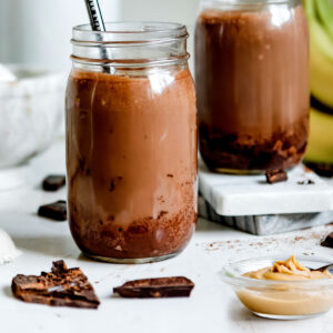 Chocolate peanut butter smoothie in two jars with straws.