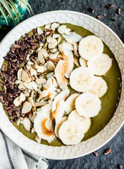 vegan smoothie bowl topped with bananas, toasted coconut and cacao nibs.