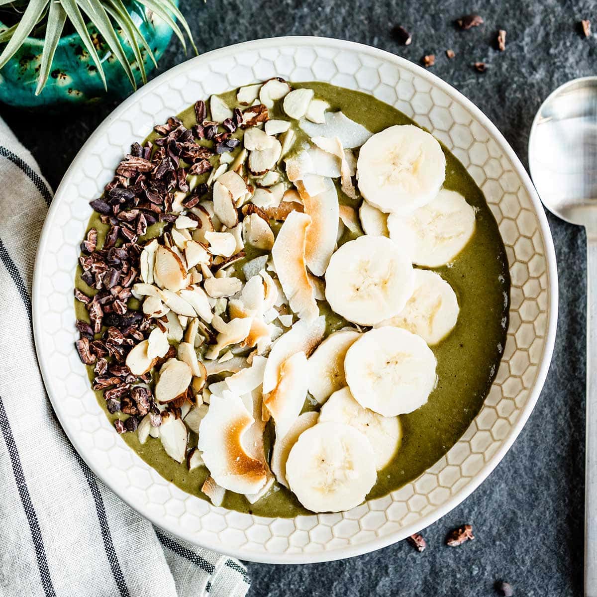 vegan smoothie bowl topped with bananas, toasted coconut and cacao nibs.