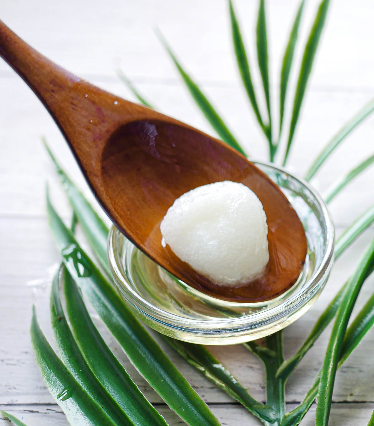 coconut oil in solid and liquid form on a wooden spoon.