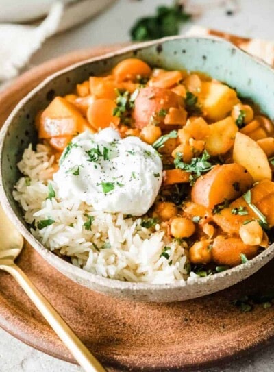 vegan potato curry with cashew cream and rice in a bowl with a gold spoon.