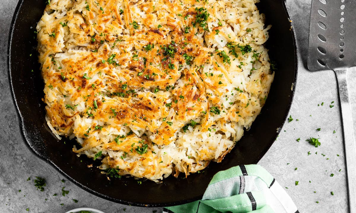 finished hash brown recipe in cast iron skillet with fresh parsley.