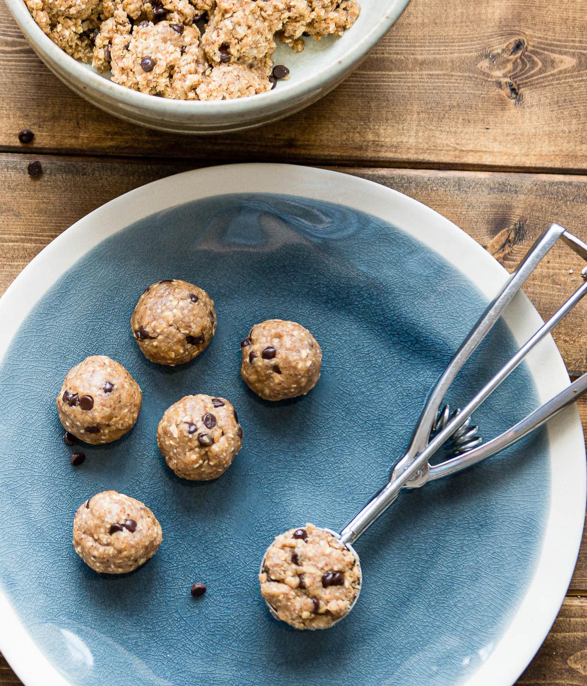 no-bake energy balls, one in a cookie scoop, one a blue plate.