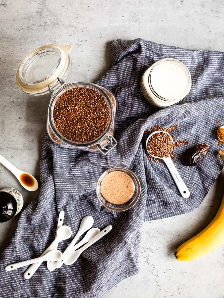 ingredients for a smoothie including plant-based milk, flaxseeds, dates, cinnamon, vanilla and almond butter.