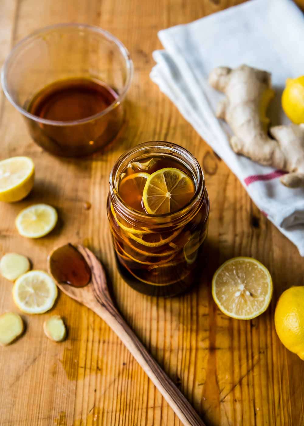 Open jar of homemade Ginger Lemon Honey Tea next to a wooden spoon.