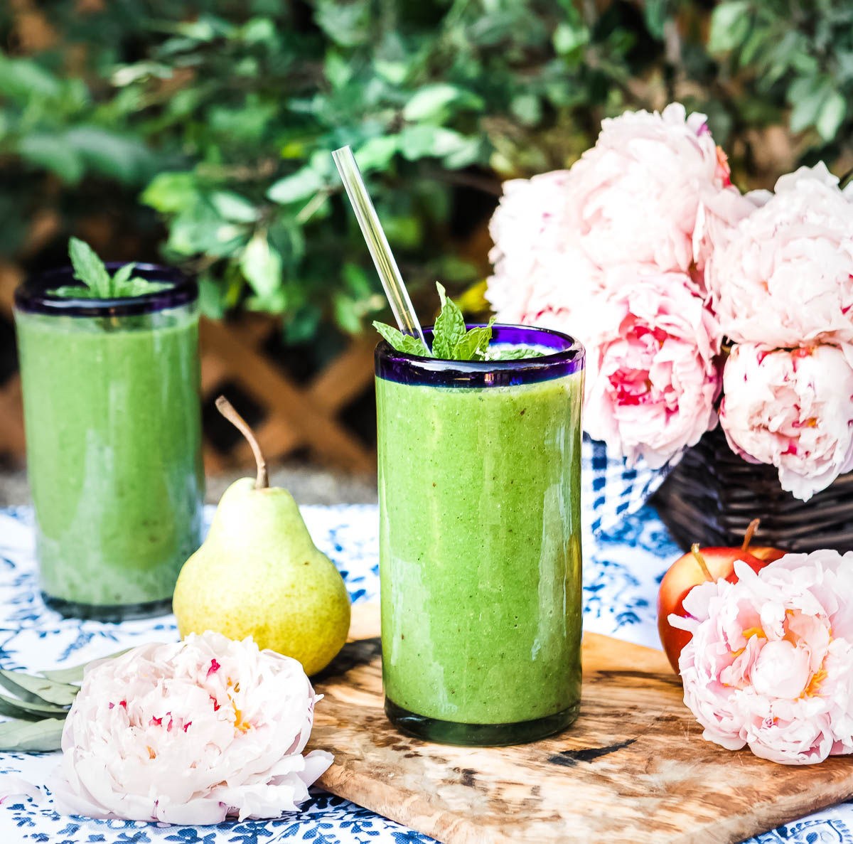 2 glasses of green smoothie recipe for glowing skin topped with fresh mint and a glass straw.