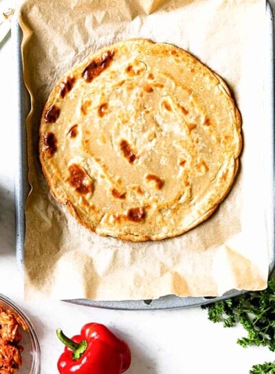 gluten-free pizza crust on a parchment lined baking sheet.