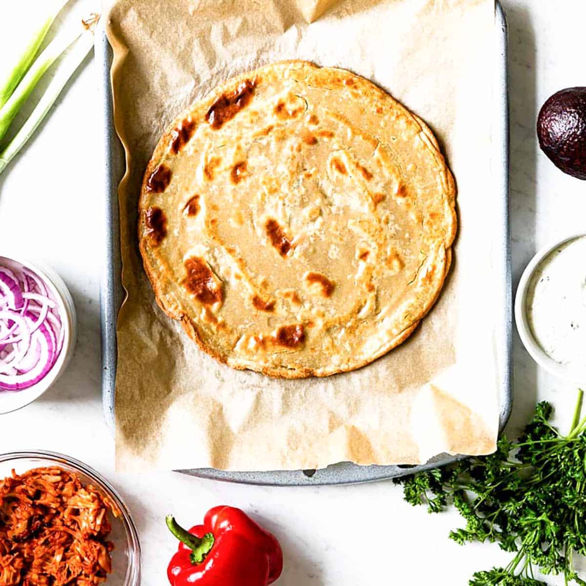 gluten-free pizza crust on a parchment lined baking sheet.