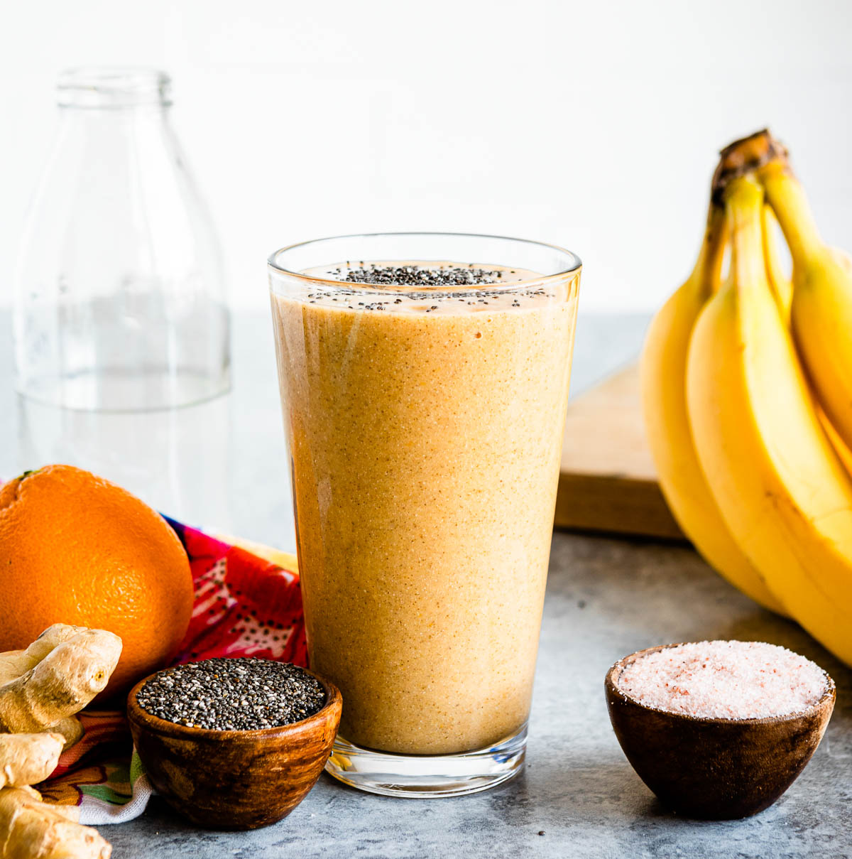 hangover smoothie in a glass next to wooden bowls of chia seeds and Himalayan sea salt.