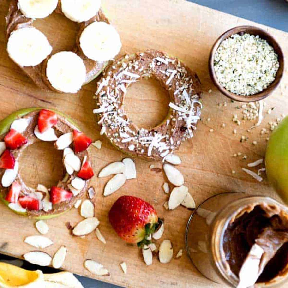 healthy snacks for weight loss including apple rings with nut butter and fruit toppings.