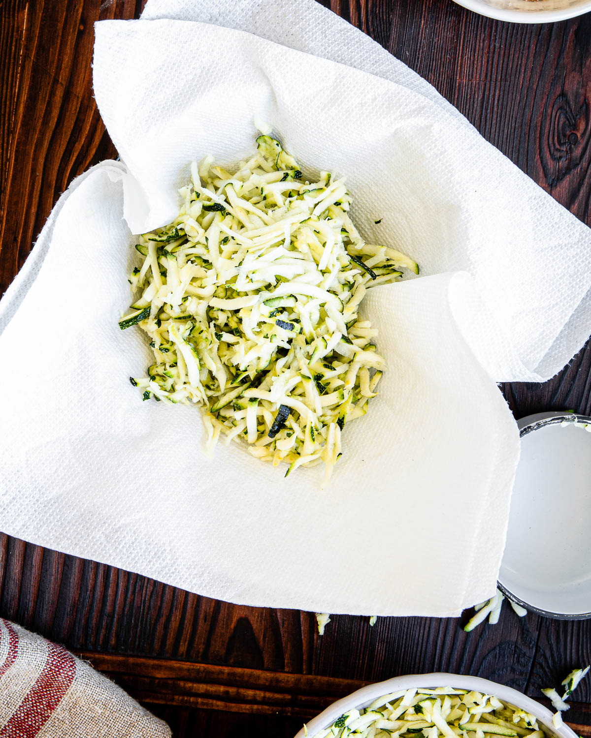 two paper towels with shredded zucchini.