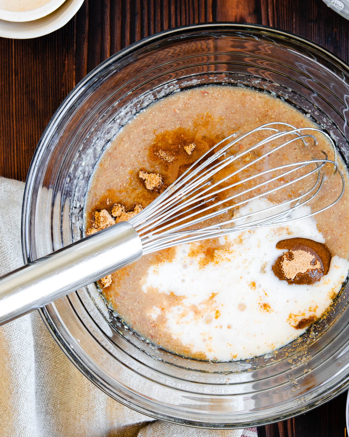 glass bowl with several mixed ingredients for zucchini bread recipe and a whisk.