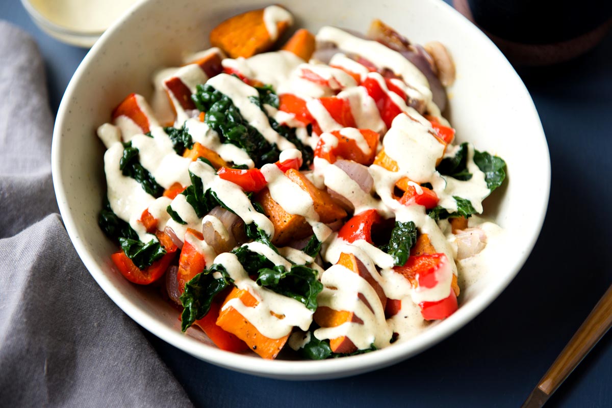 Table set for dinner with veggie bowl and creamy hemp hearts sauce on top.