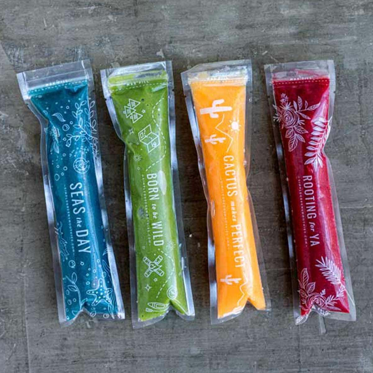 4 plastic sleeves filled with healthy homemade popsicles in blue, green, yellow and red.