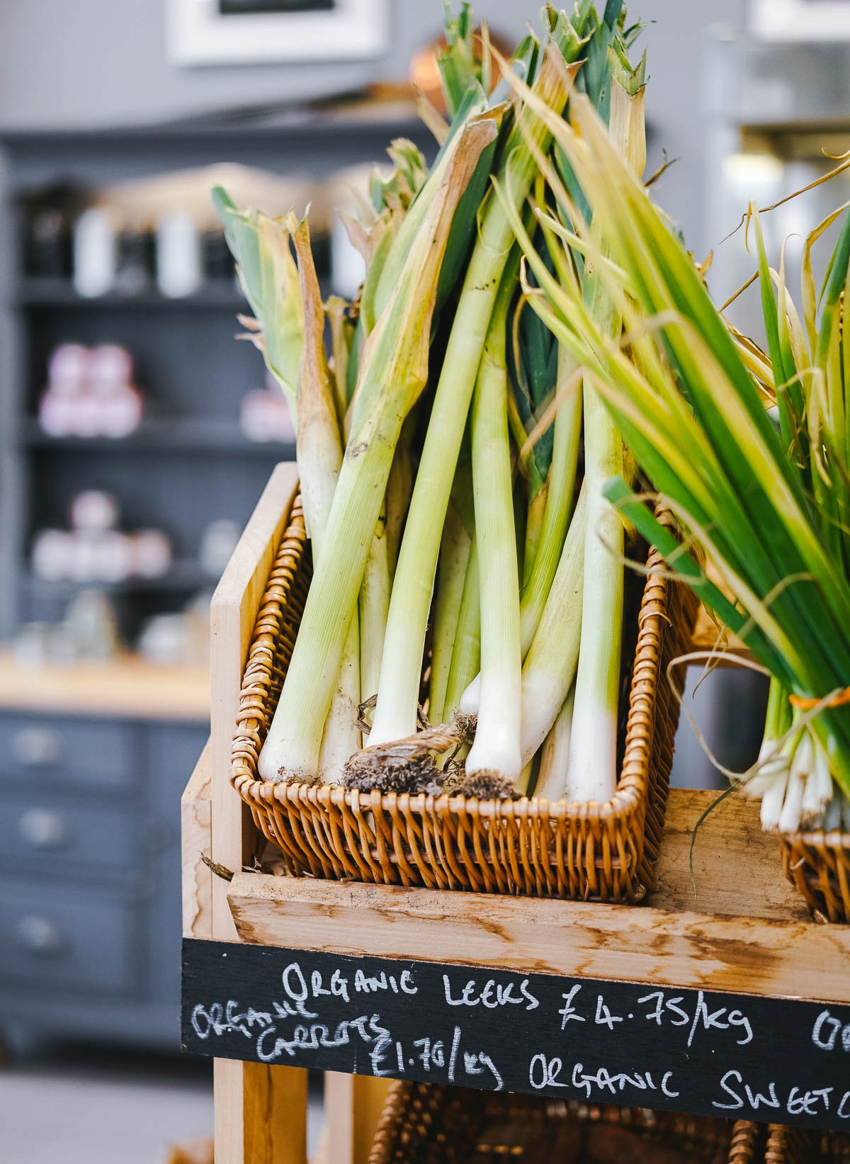 woven basket full of a bunch of fresh, whole leeks.