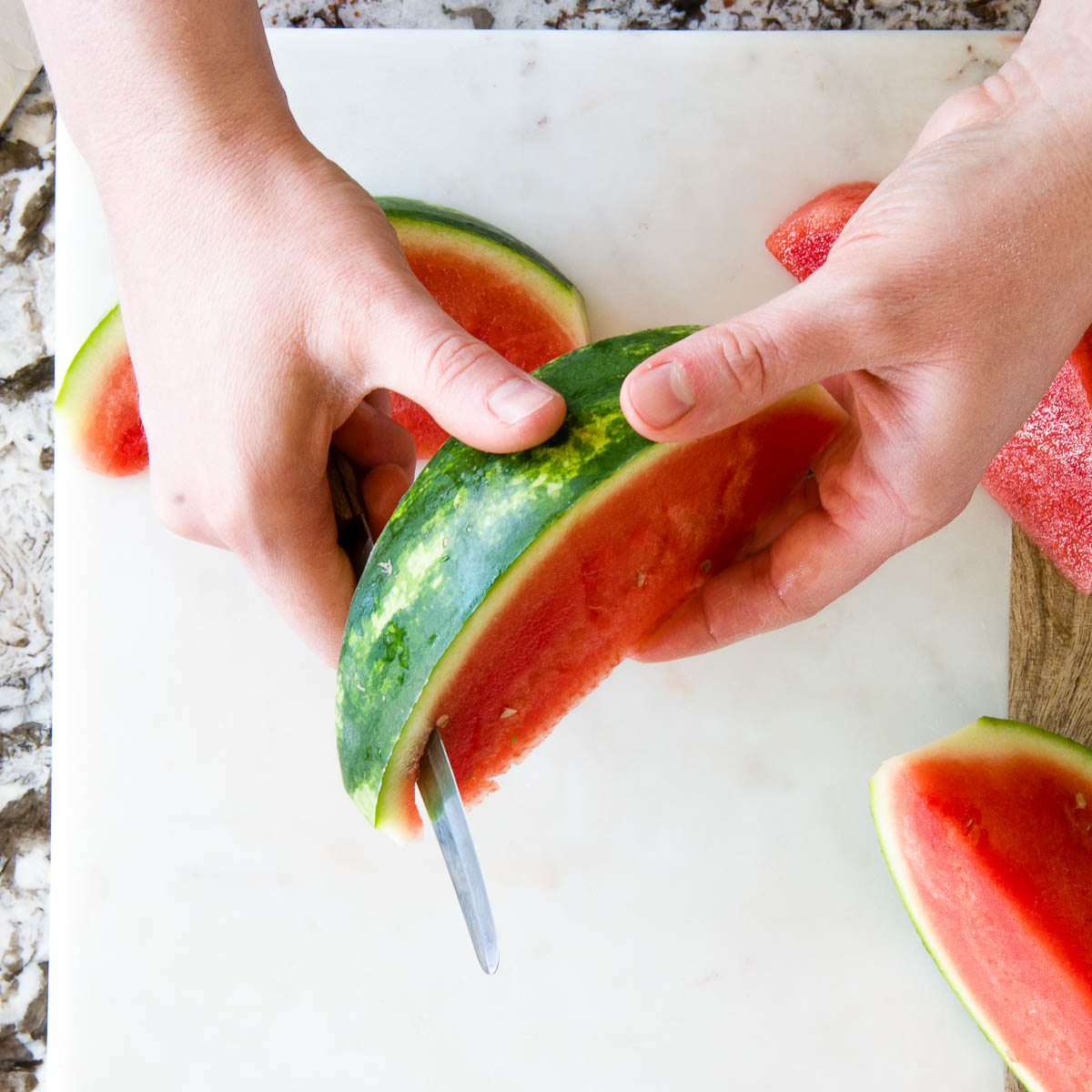 slicing away the rind from the watermelon.