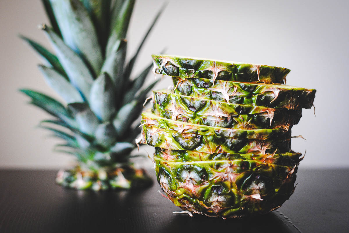 sliced layers of pineapple with the skin on stacked on each other.