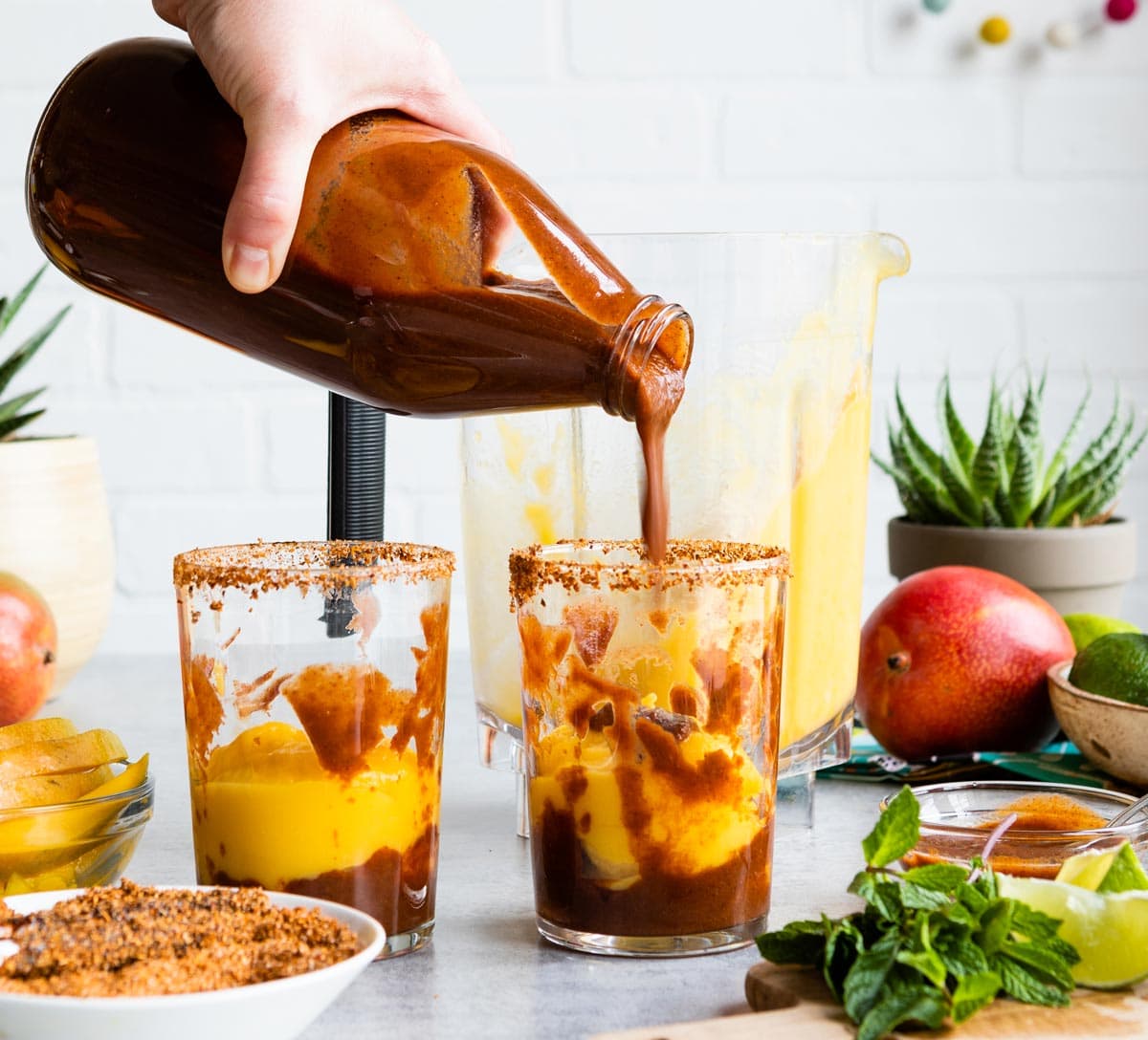 layering mango lime smoothie and chamoy sauce for mangonada recipe.