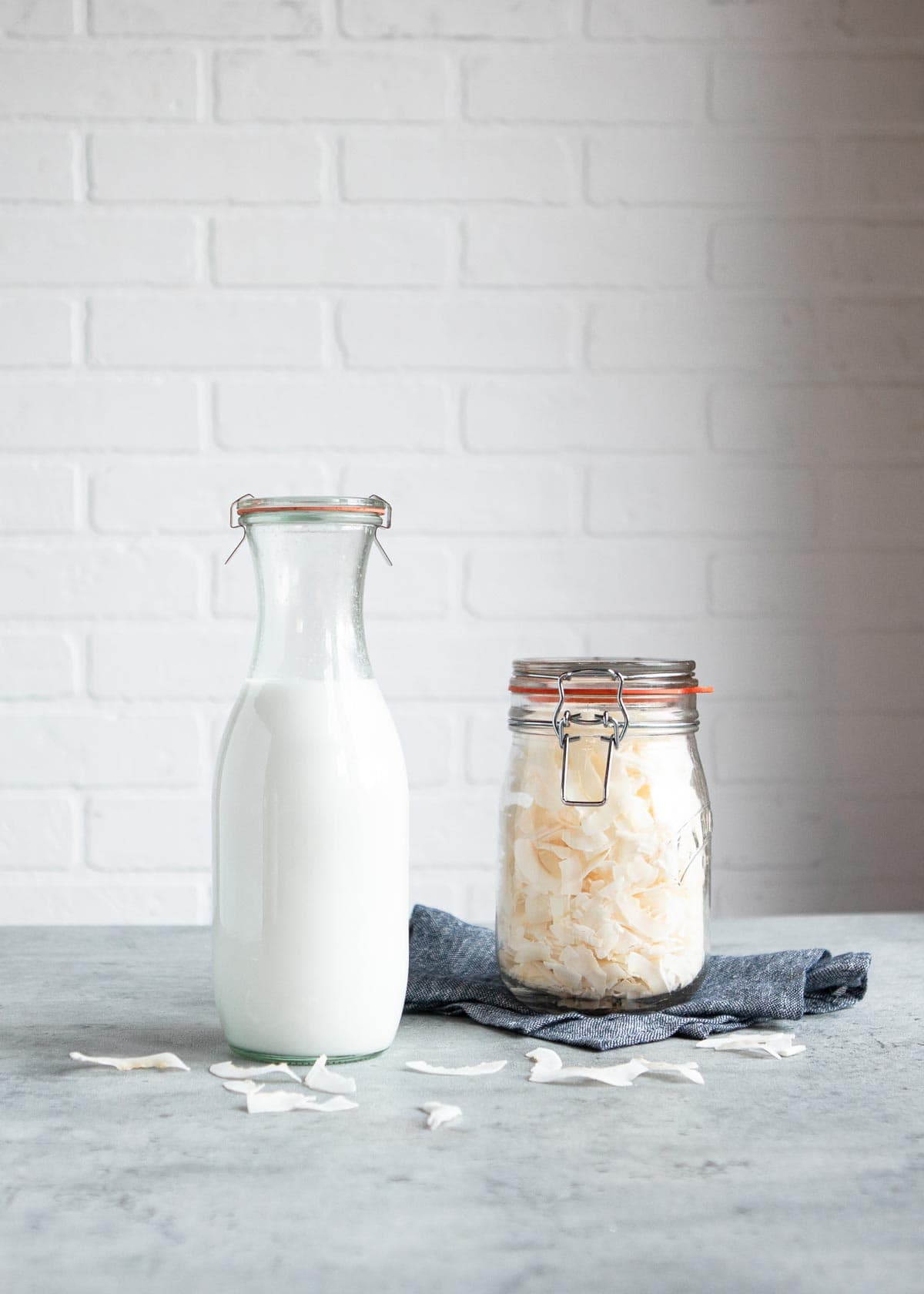 perfect diy beverage in glass pitcher next to a container of dried coconut flakes.