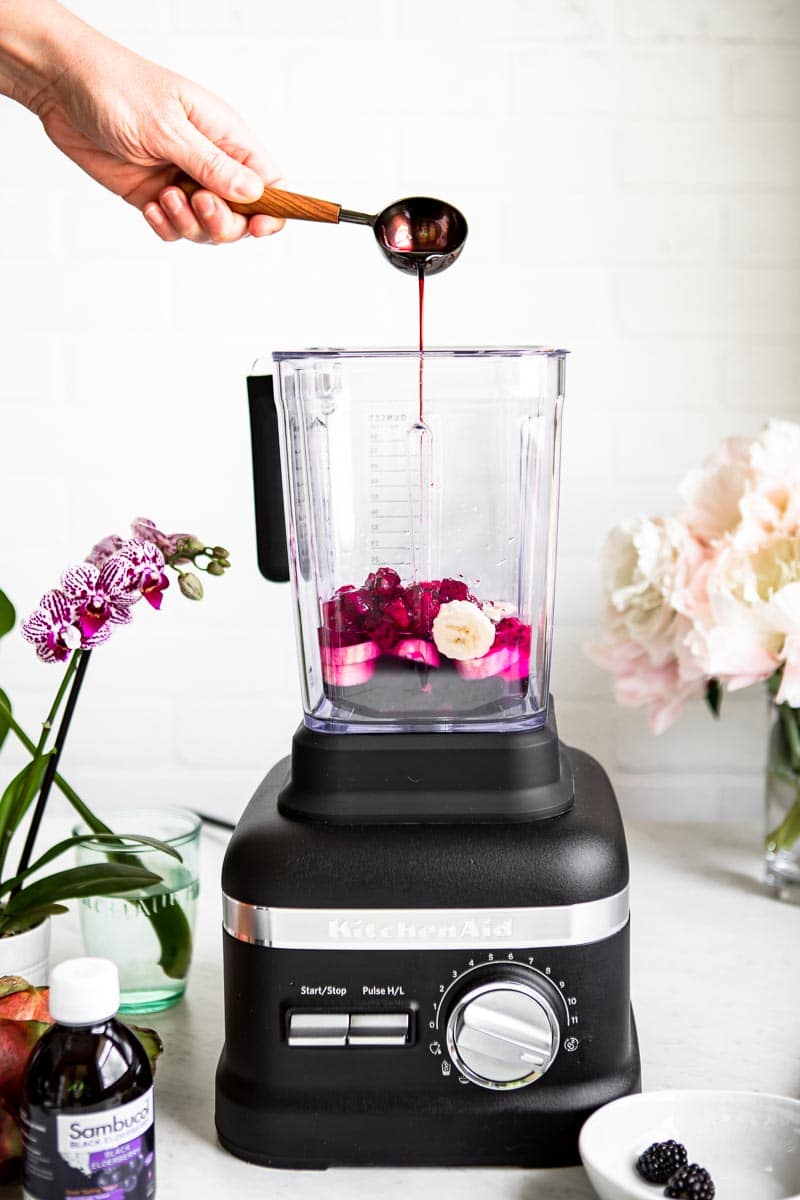 Adding elderberry syrup to a smoothie recipe.