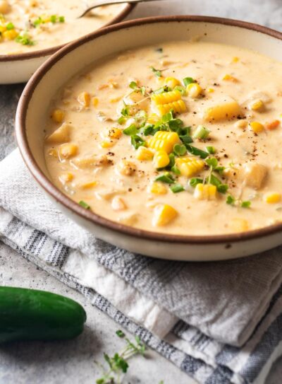 White bowl of vegan corn chowder and jalapeno pepper on the side.