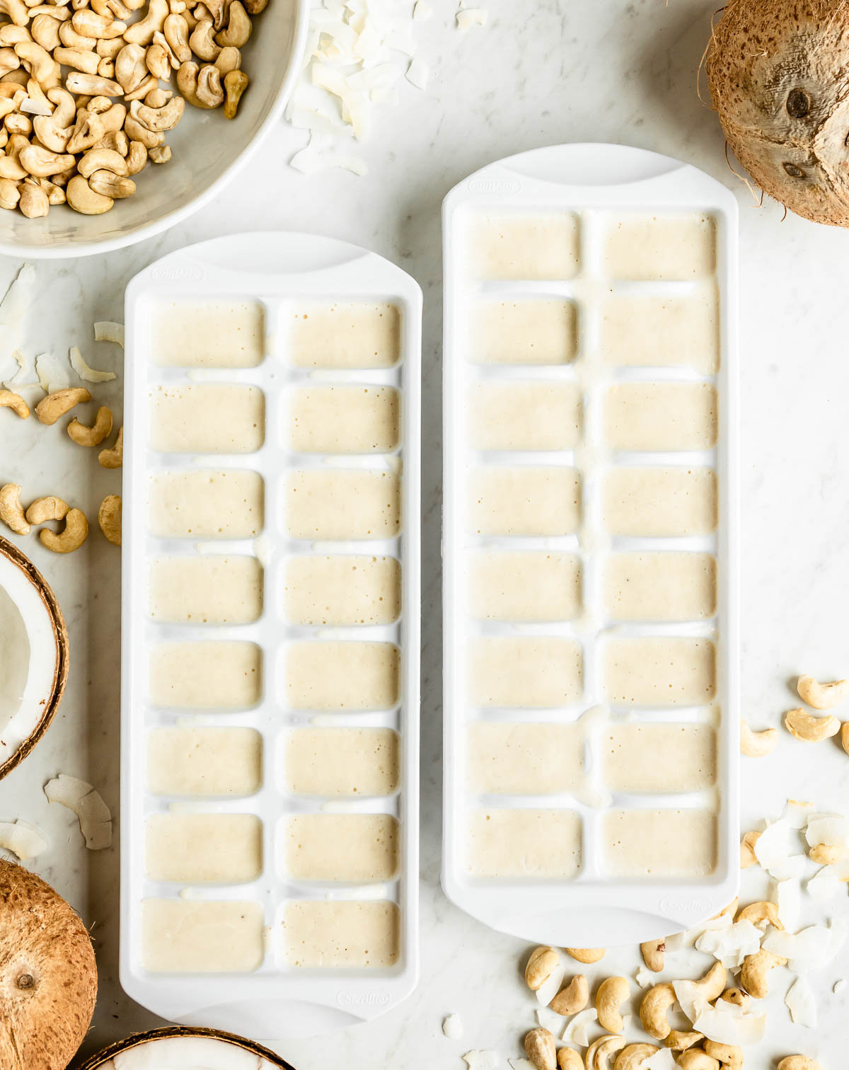 2 ice cube trays full of cream colored cubes.