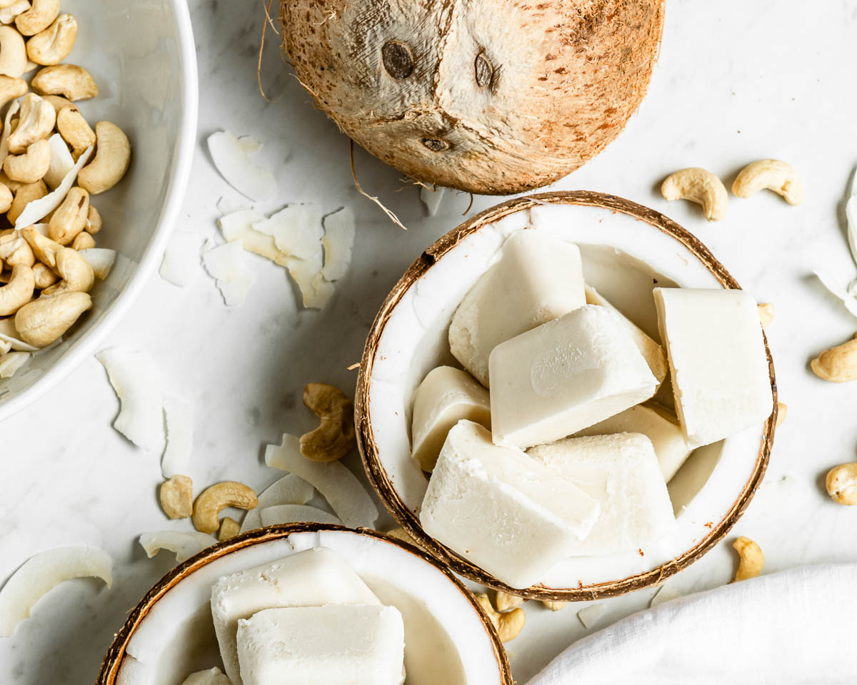 smoothie cubes in coconuts on a white counter.