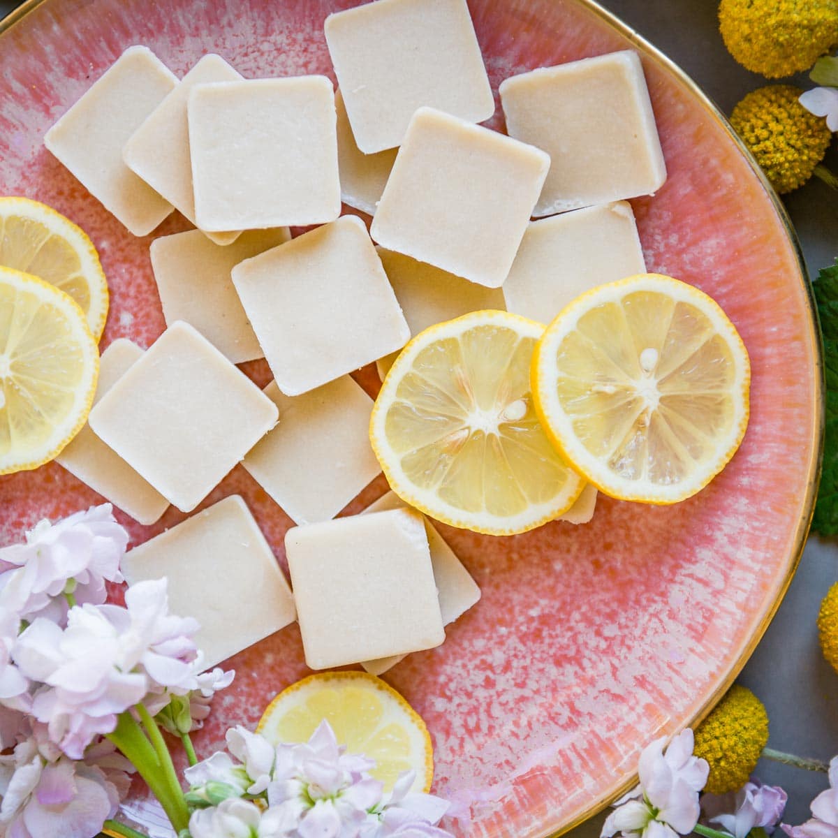 pink plate full of lemon fat bombs and fresh lemon slices.