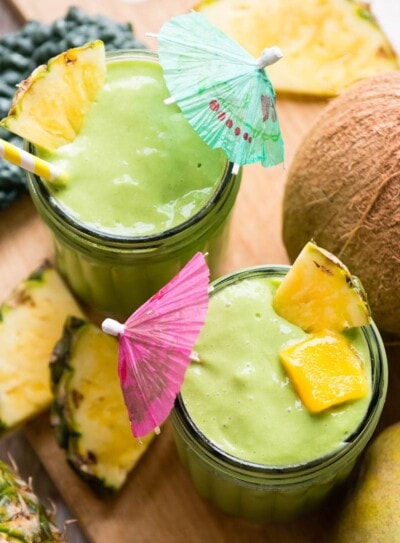 mango kale smoothie in glasses with tropical umbrellas.