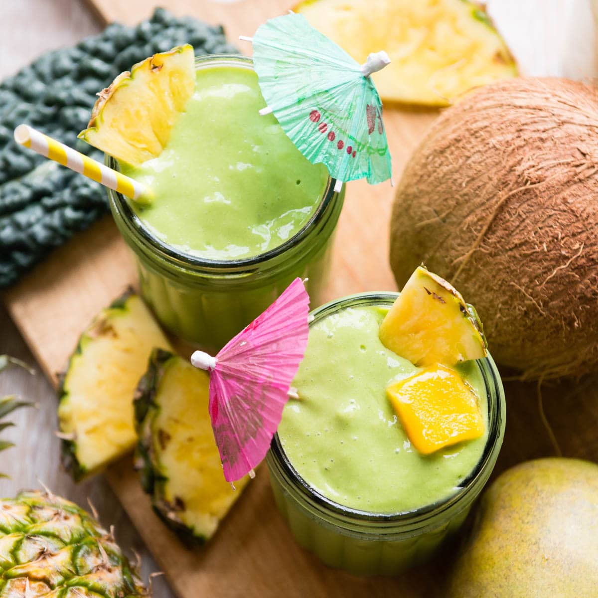 mango kale smoothie in glasses with tropical umbrellas.