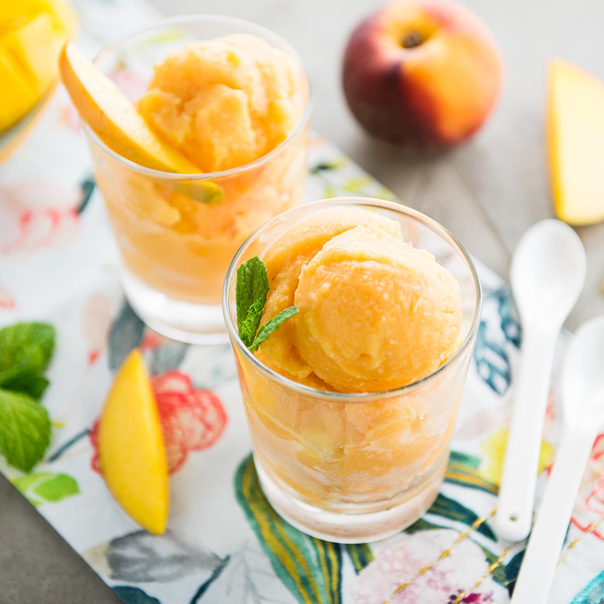 2 glasses of fresh mango sorbet on a colorful tea towel.