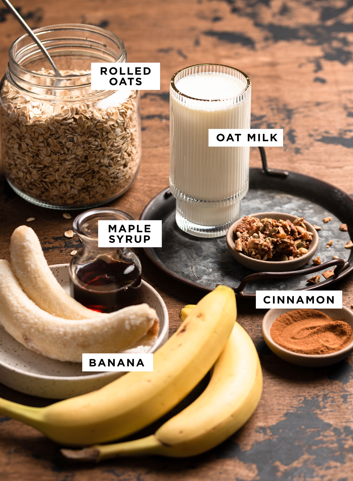 labeled ingredients for an oat smoothie bowl including rolled oats, oat milk, cinnamon, maple syrup and banana.